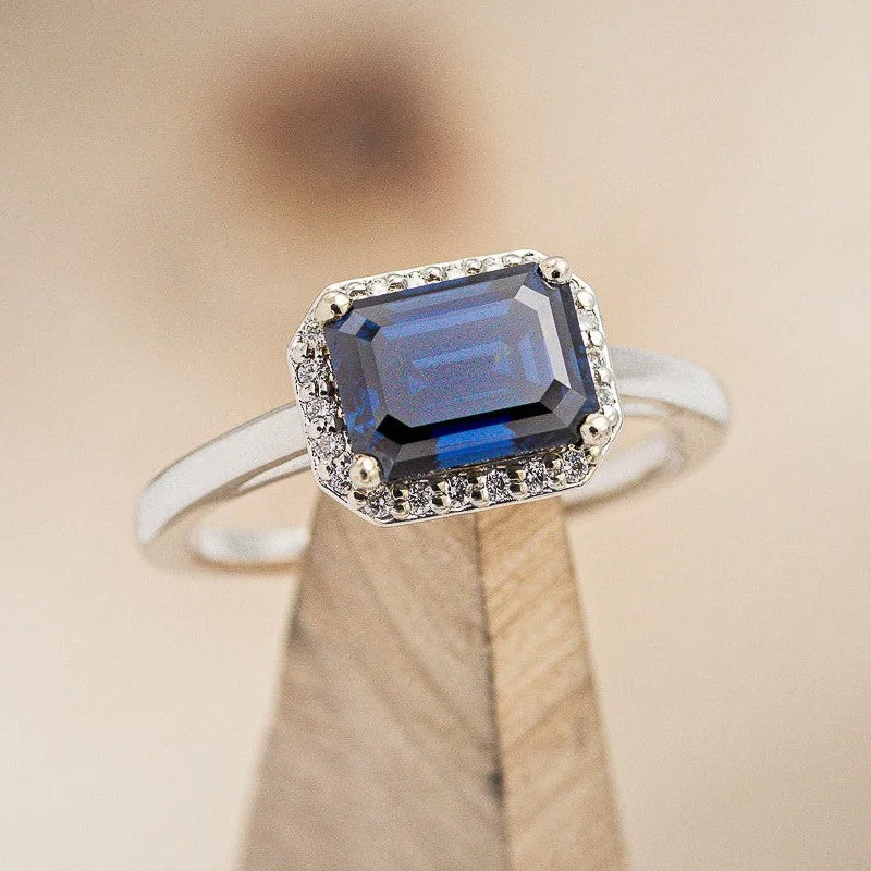 "CYBELE" - EMERALD CUT ACTAEON BLUE MOISSANITE ENGAGEMENT RING WITH DIAMOND HALO